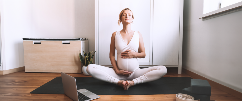 Meditierende Schwangere hält zärtlich ihren Babybauch.